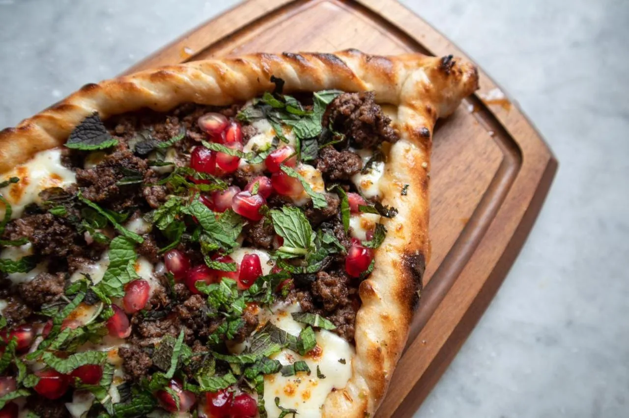a pizza sitting on a wooden cutting board at Hope Street Hotel in Liverpool